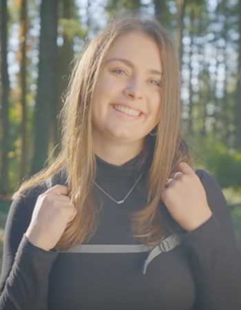 Audrey smiling with backpack in the woods near UO campus