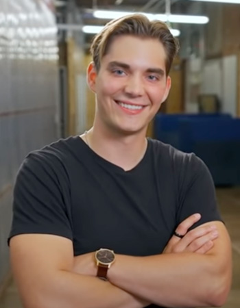 Connor smiling with arms crossed in classroom on UO campus