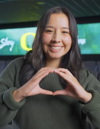 Gabby throwing O in front of screen on UO campus