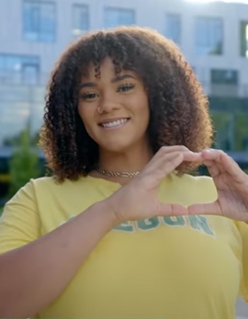 Gemma smiles while throwing the O in front of Tykeson Hall on UO campus