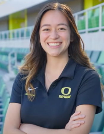 Natasha smiling with arms crossed in Hayward Field on UO campus