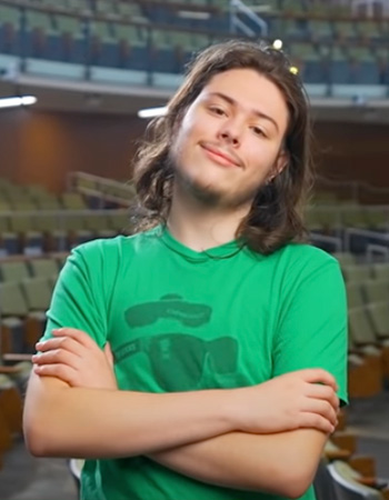 Meet Zach standing crossed armed in UO classroom on campus